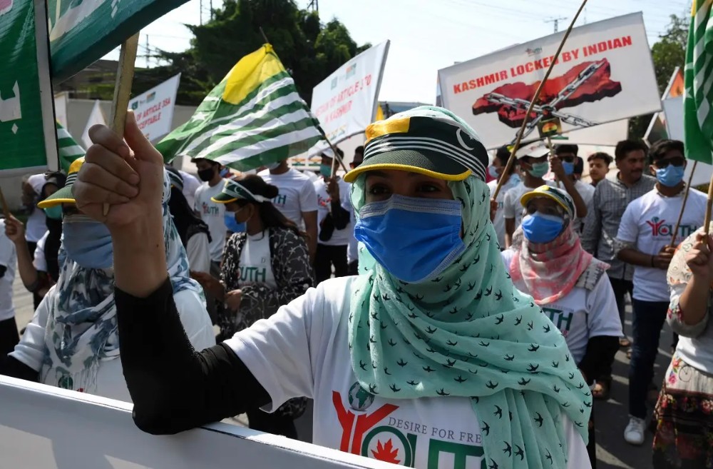 Activists of Pakistan Youth Forum Kashmir hold placards and wave Azad Kashmir flags during a rally to show their solidarity with people of Indian-administered Kashmir, in Lahore, on August 5, 2020. (AFP)