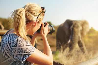 a woman taking a photo of an elephant on a safari