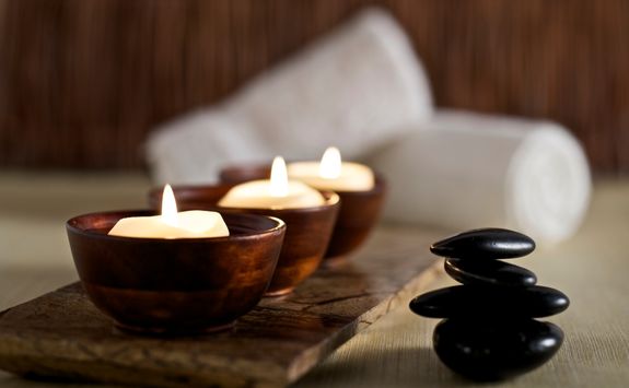 lit candles and black massage stones