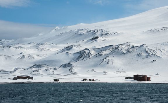 abandoned whaling station with snowy mountain in the background