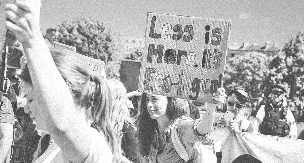Women Protesting with a sign that says less is more ecological