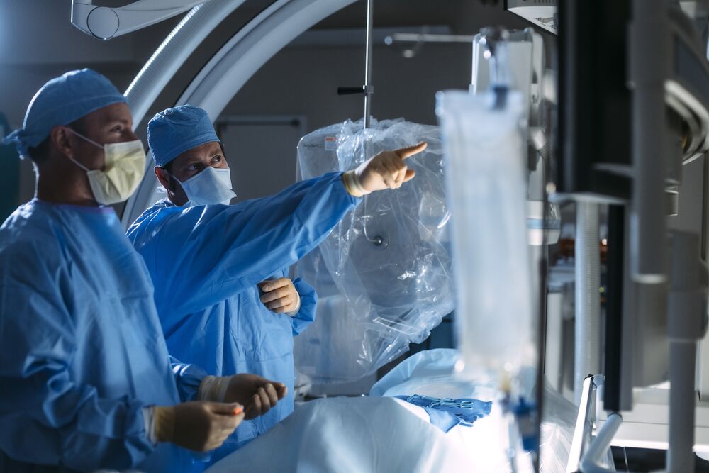 Two Doctors in A Surgery Room with One Doctor Pointing to The Image Guided Screens | Semmes Murphey