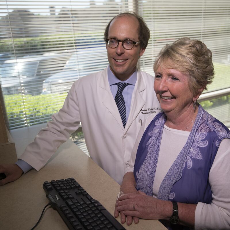 a doctor and a patient smiling and looking at a computer