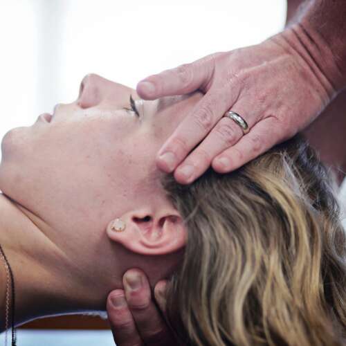 A female physical therapy patient with her neck and head held by a therapist