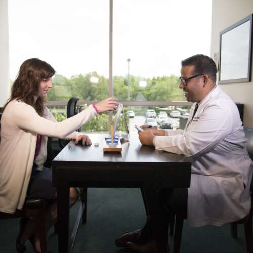 Doctor and patient sitting at a desk while the patient does cognitive testing