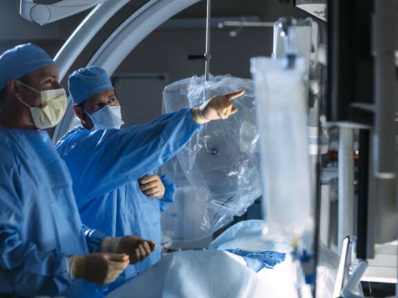Two Doctors in A Surgery Room with One Doctor Pointing to The Image Guided Screens | Semmes Murphey
