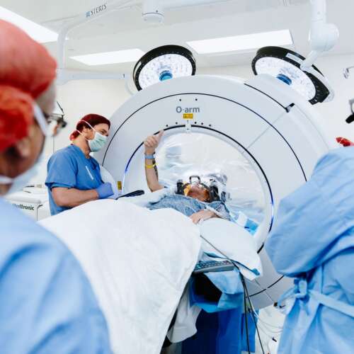 Operating room with a patient undergoing an outpatient brain surgery and holding up a thumbs up
