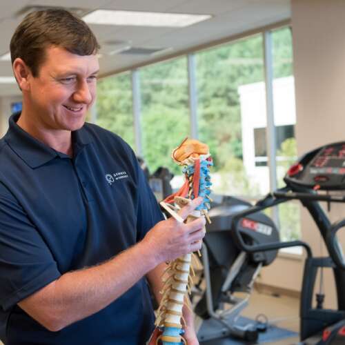 Male physical therapist holding a spine model