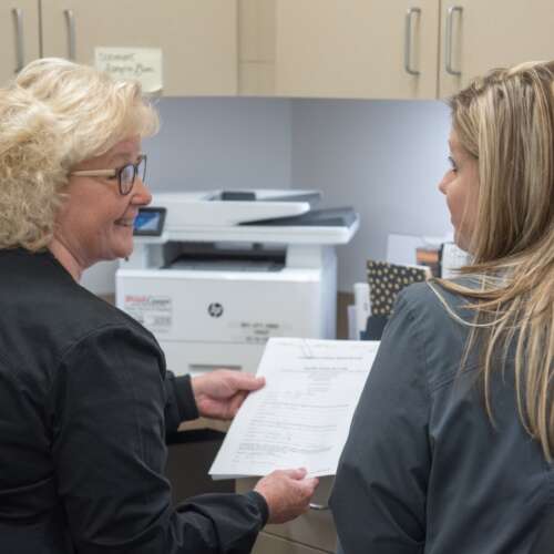 two female nurses looking at paperwork with a printer in the background