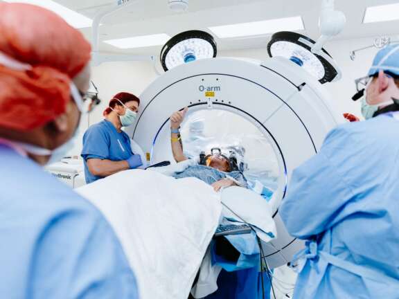 Operating room with a patient undergoing an outpatient brain surgery and holding up a thumbs up