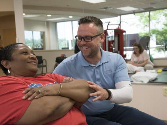 Male physical therapist working with a female patient laying on her back
