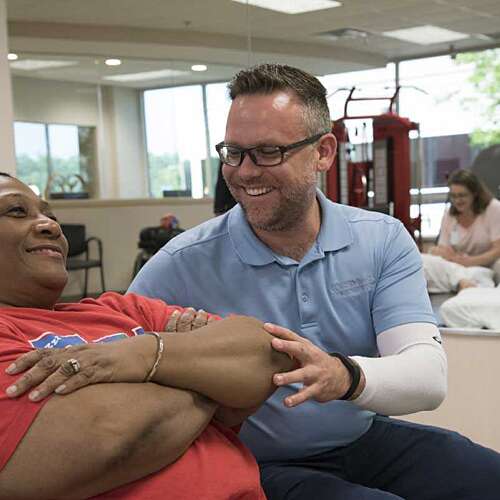 Male physical therapist working with a female patient laying on her back