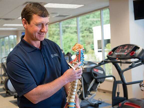 Male physical therapist holding a spine model