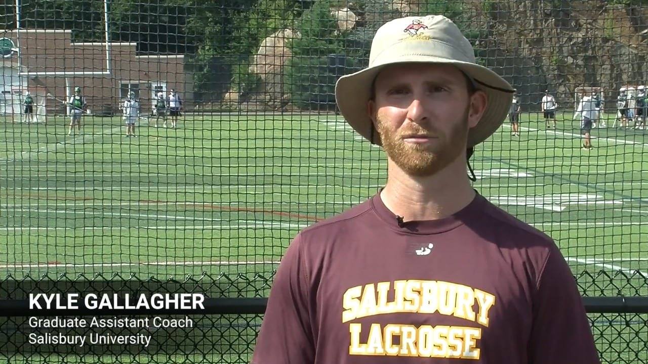 College lacrosse coach speaking to camera on the field