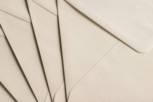 A close-up view of several beige envelopes arranged in a fanned-out pattern, showing their flaps neatly overlapping each other.