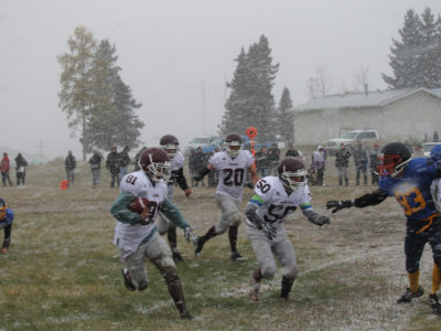 Beauval Voyageur #81 Kolby Bouvier running the ball against the snow and Sandy Bay