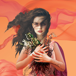 Woman with long, flowing hair holding a bouquet of white flowers in front of an abstract orange and pink background.