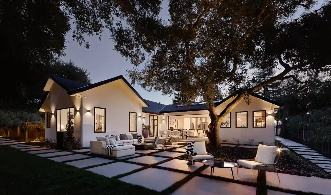 Renovated home with a large outdoor patio and seating area illuminated at dusk. Renovated home with a large outdoor patio and seating area illuminated at dusk.