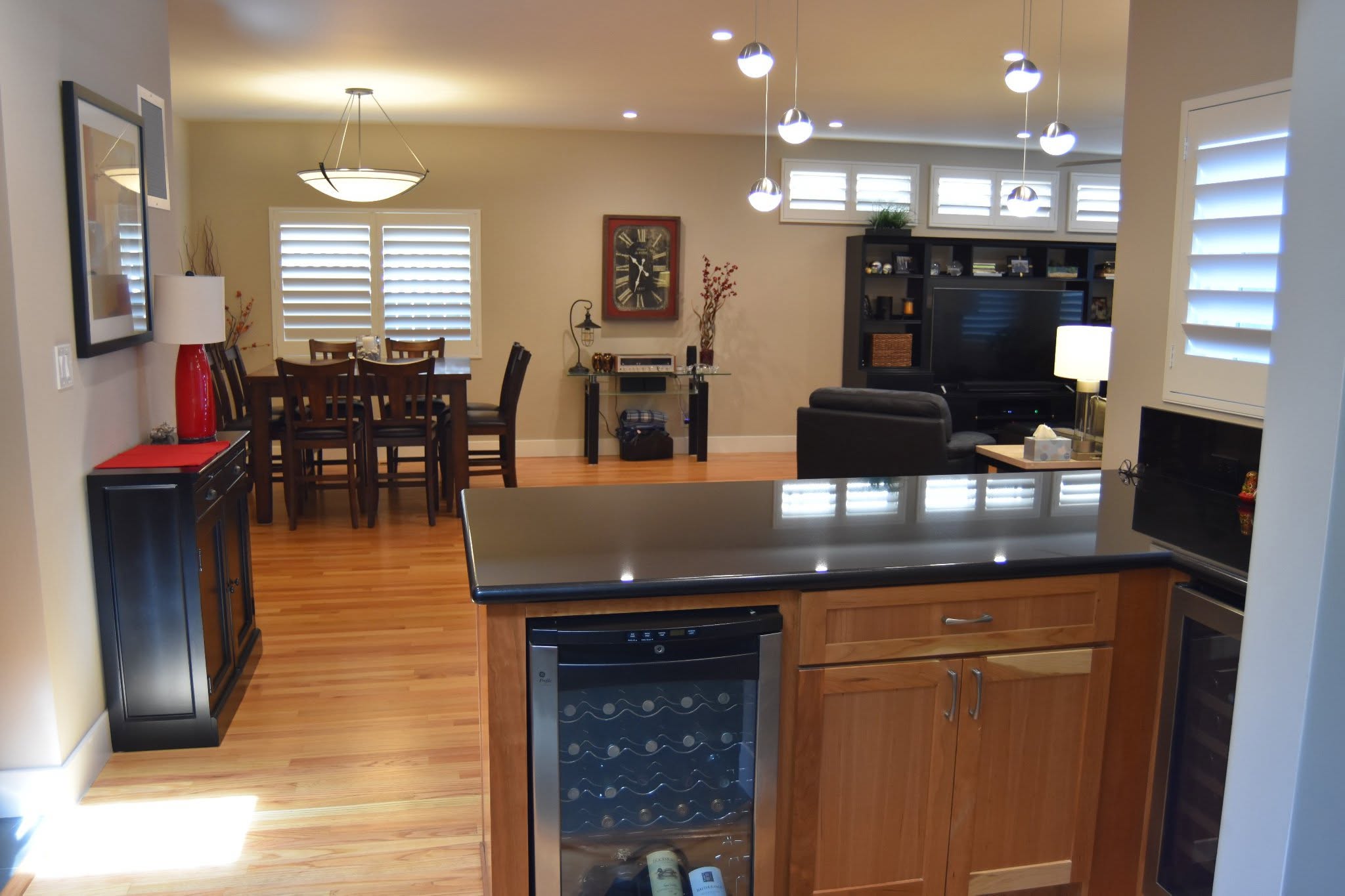 A remodeled kitchen and dining area in an older home with hardwood floors, wood cabinetry, and updated lighting