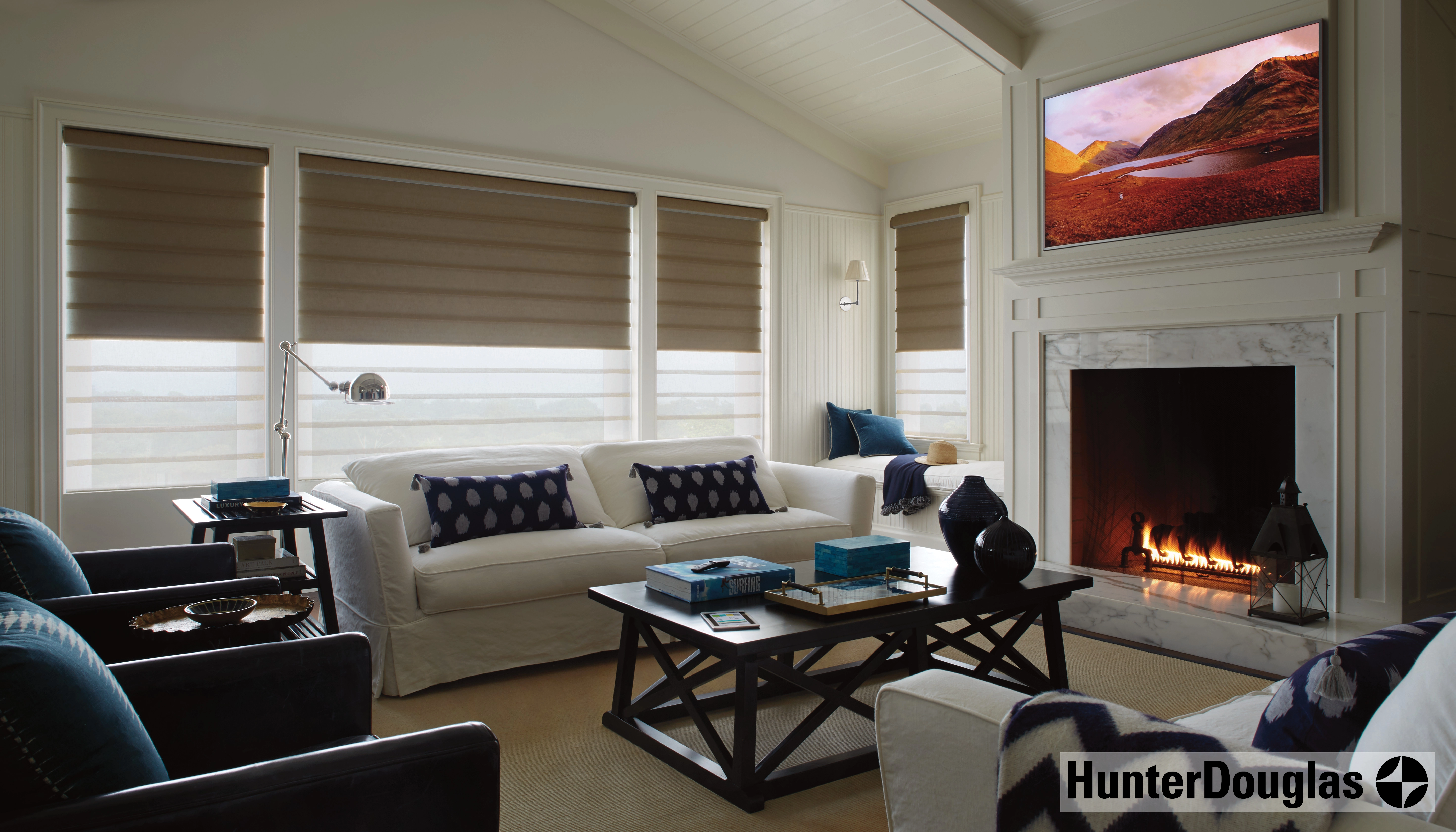 Living room with taupe window shades, white sofas, blue cushions, a marble fireplace, and a wall-mounted TV. Living room with taupe window shades, white sofas, blue cushions, a marble fireplace, and a wall-mounted TV.