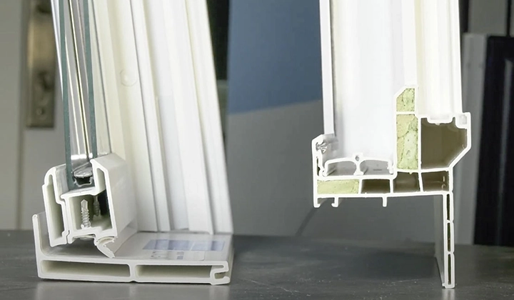 Two window frame cross-sections displayed on a surface, showing intricate internal structures and insulation materials. Two window frame cross-sections displayed on a surface, showing intricate internal structures and insulation materials.
