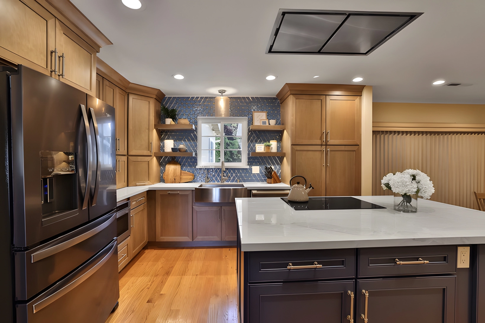 Modern kitchen with light wood cabinets, dark appliances, a large island with a white countertop, and decorative shelving above a sink. Modern kitchen with light wood cabinets, dark appliances, a large island with a white countertop, and decorative shelving above a sink.