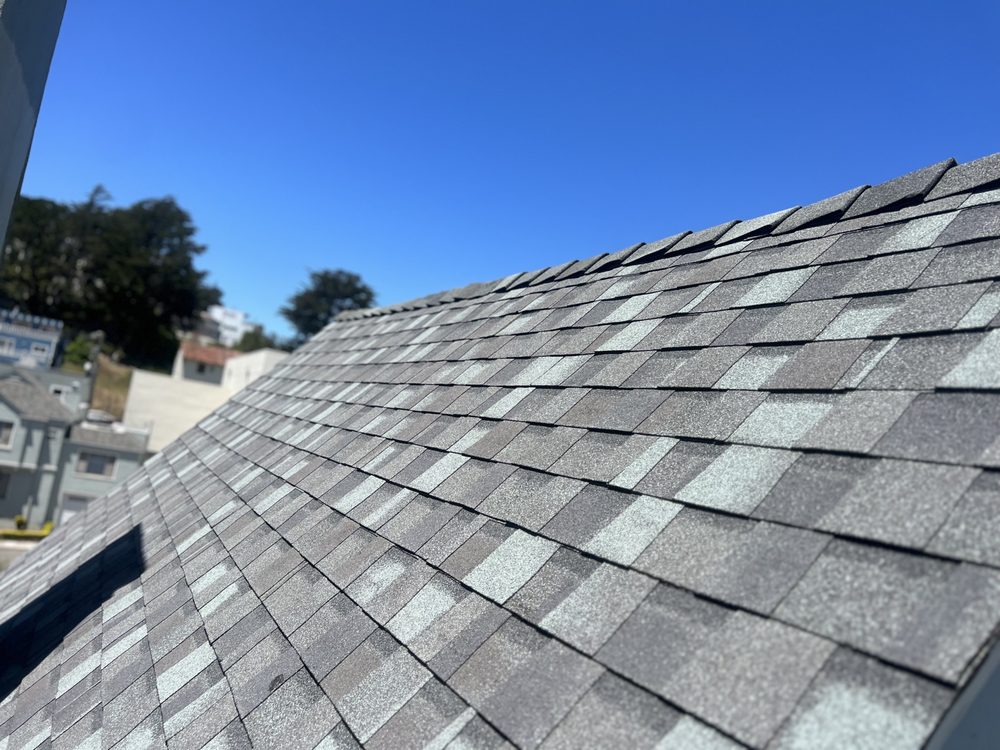 Close-up of gray asphalt shingles installed on a sloped residential roof. Close-up of gray asphalt shingles installed on a sloped residential roof.