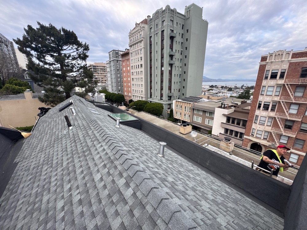 Gray asphalt shingle roof on a multi-story residential building in an urban neighborhood. Gray asphalt shingle roof on a multi-story residential building in an urban neighborhood.