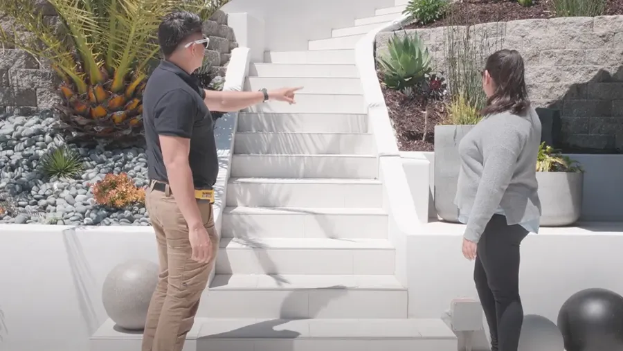 Two people stand by a white staircase built into a landscaped hillside, pointing and discussing details. Two people stand by a white staircase built into a landscaped hillside, pointing and discussing details.