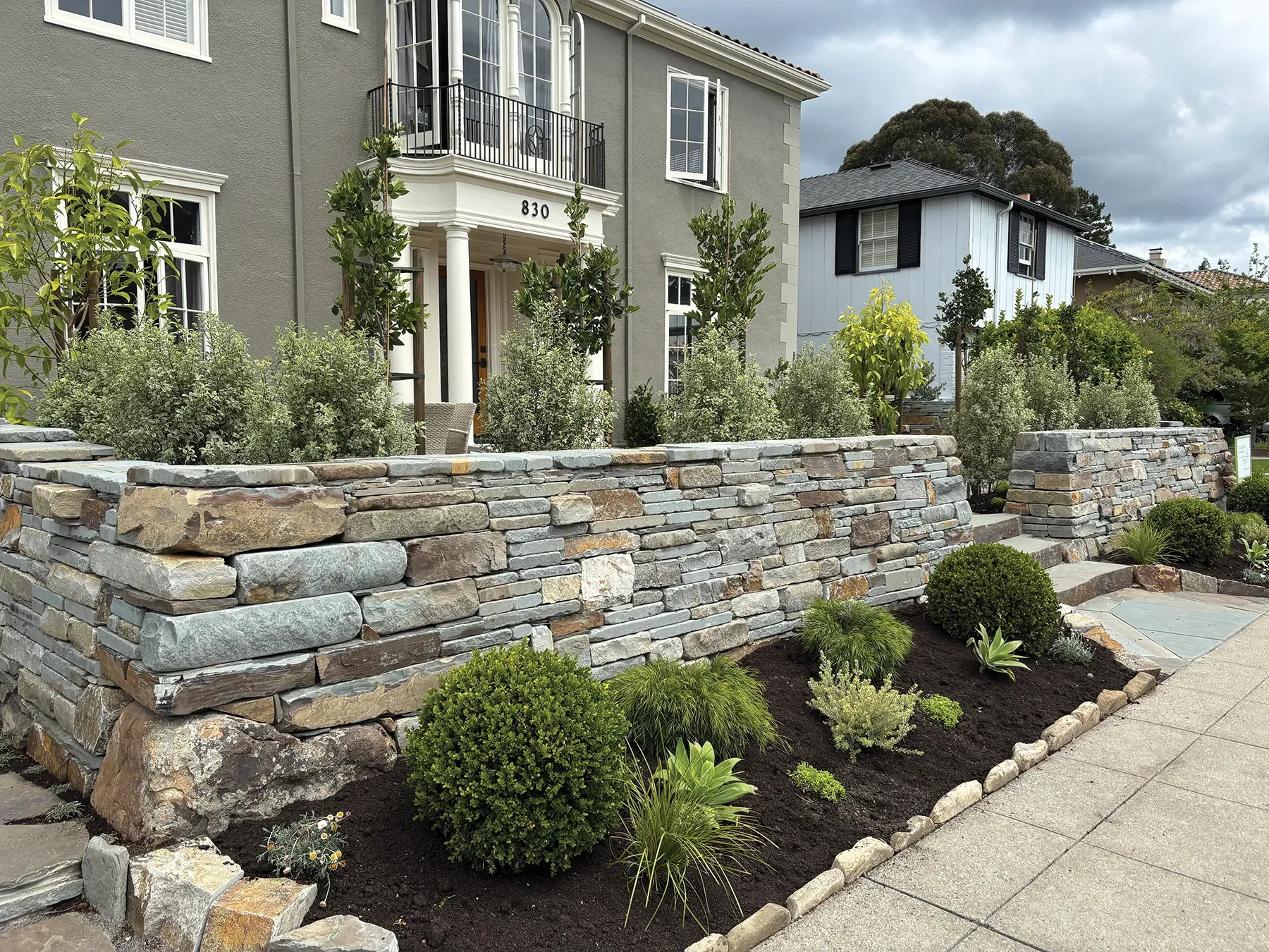 This beautifully designed outdoor space showcases a harmonious blend of natural stone elements and lush greenery. The landscaping features expertly placed large oak stones that form a rustic yet refined boundary around a soft, manicured lawn area. Complementing the stones are a variety of plants and shrubs, adding texture and vibrant color. The layout offers both aesthetic appeal and functional outdoor living space, perfect for relaxation or gatherings. The combination of earthy tones and organic shapes creates a serene and inviting atmosphere, highlighting expert craftsmanship in stone landscaping design. This beautifully designed outdoor space showcases a harmonious blend of natural stone elements and lush greenery. The landscaping features expertly placed large oak stones that form a rustic yet refined boundary around a soft, manicured lawn area. Complementing the stones are a variety of plants and shrubs, adding texture and vibrant color. The layout offers both aesthetic appeal and functional outdoor living space, perfect for relaxation or gatherings. The combination of earthy tones and organic shapes creates a serene and inviting atmosphere, highlighting expert craftsmanship in stone landscaping design.
