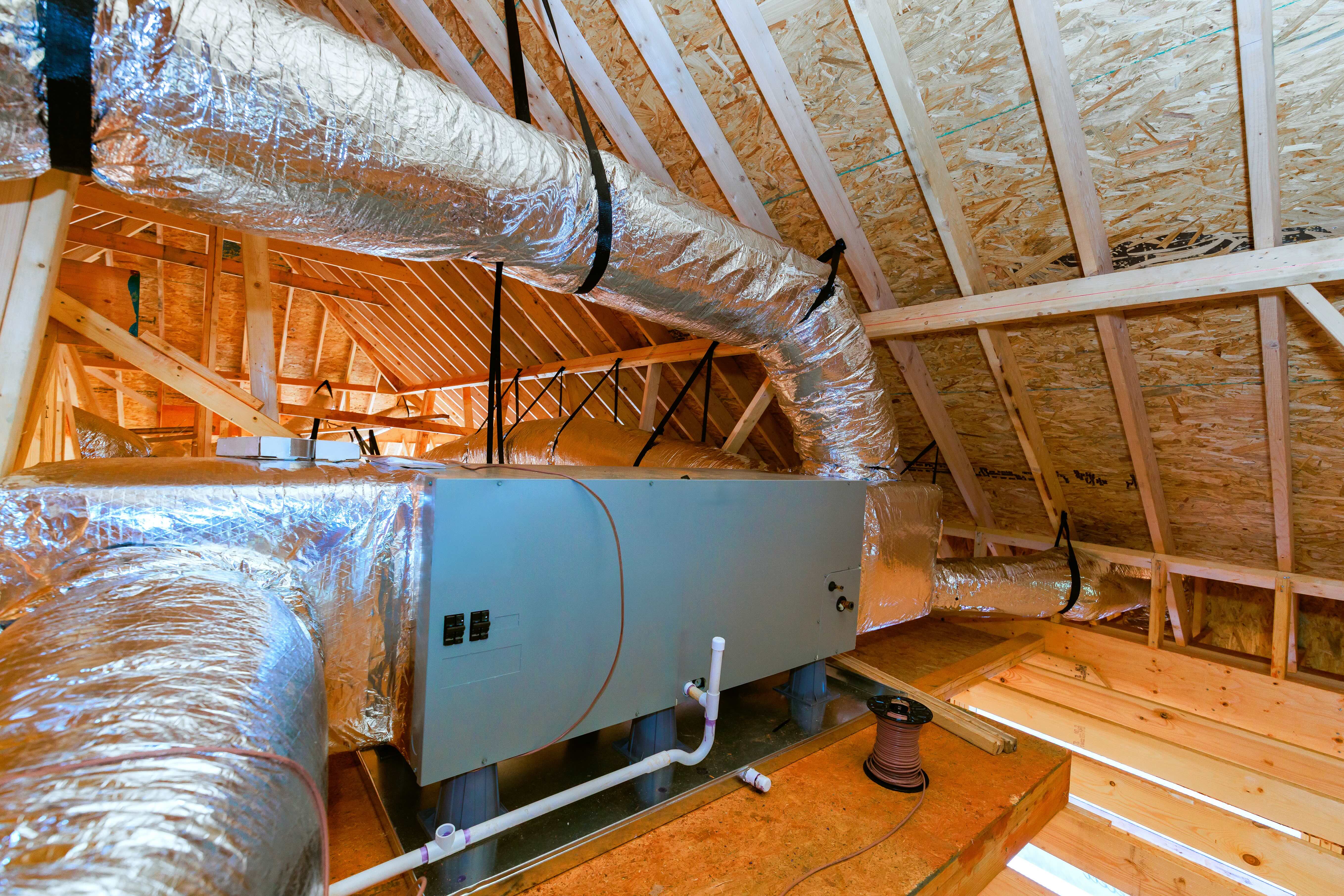 Flexible insulated HVAC ductwork connected to an air-handling unit in a residential attic.