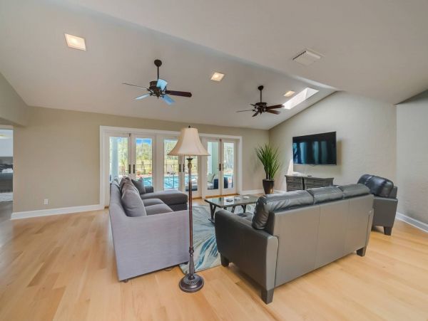 Main living room on ground floor with wall mounted TV and views of the pool and golfing green.