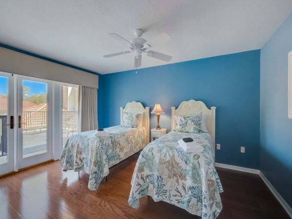 Twin room with doors to outdoor sun deck that overlooks the pool