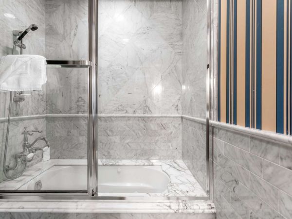 Jack N Jill bathroom with glass enclosed jetted tub and removable shower head. Small TV is mounted outside of bathtub for your enjoyment.