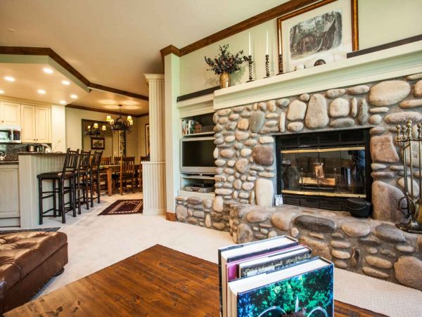 View of kitchen and dining from living room, deck access to the right of wood burning fireplace.