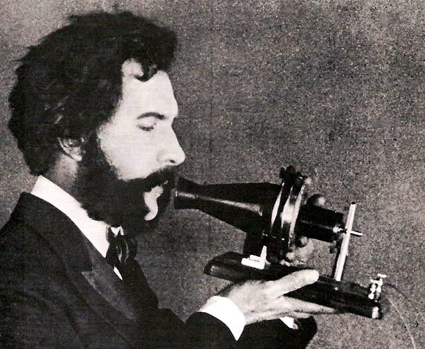 An actor portraying Alexander Graham Bell speaking into a early model of the telephone for a 1926 promotional film by AT&T, public domain. The phone is a simple conical part in which the actor is speaking, attached to a piece of wood, with no ear piece at all An actor portraying Alexander Graham Bell speaking into a early model of the telephone for a 1926 promotional film by AT&T, public domain. The phone is a simple conical part in which the actor is speaking, attached to a piece of wood, with no ear piece at all