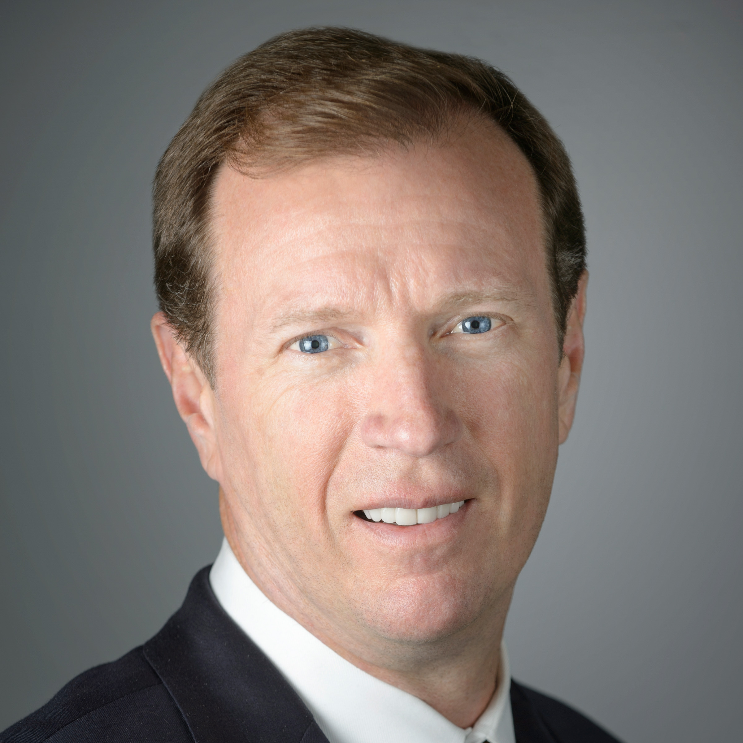 Headshot of Steve Trulaske in a suit against a gray background.