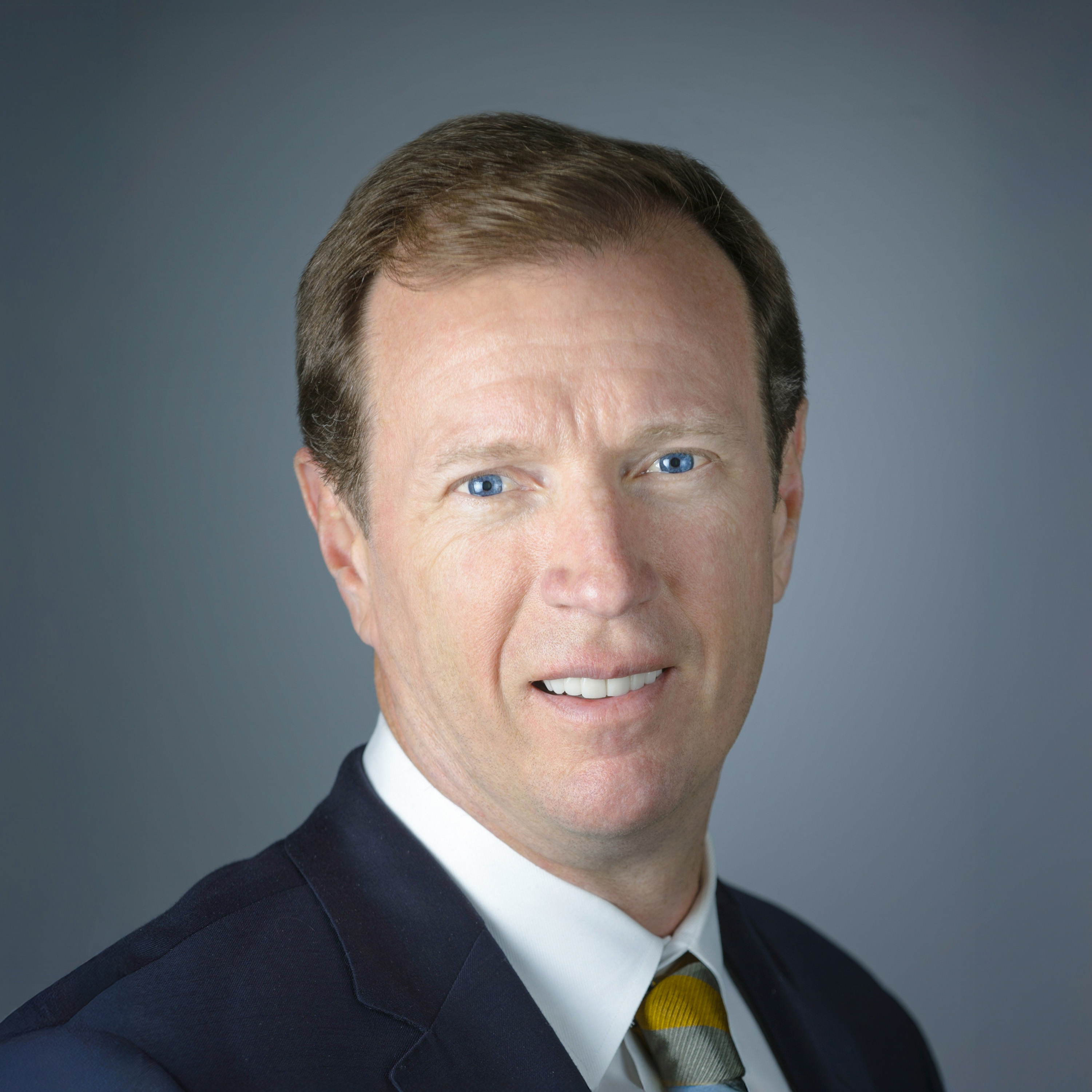 Headshot of Steven Trulaske in a suit against a gray background.
