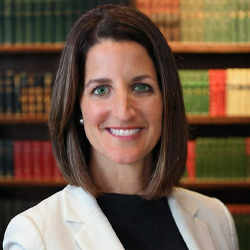 Headshot of Nichole Balkenbusch wearing a black top and white suit jacket