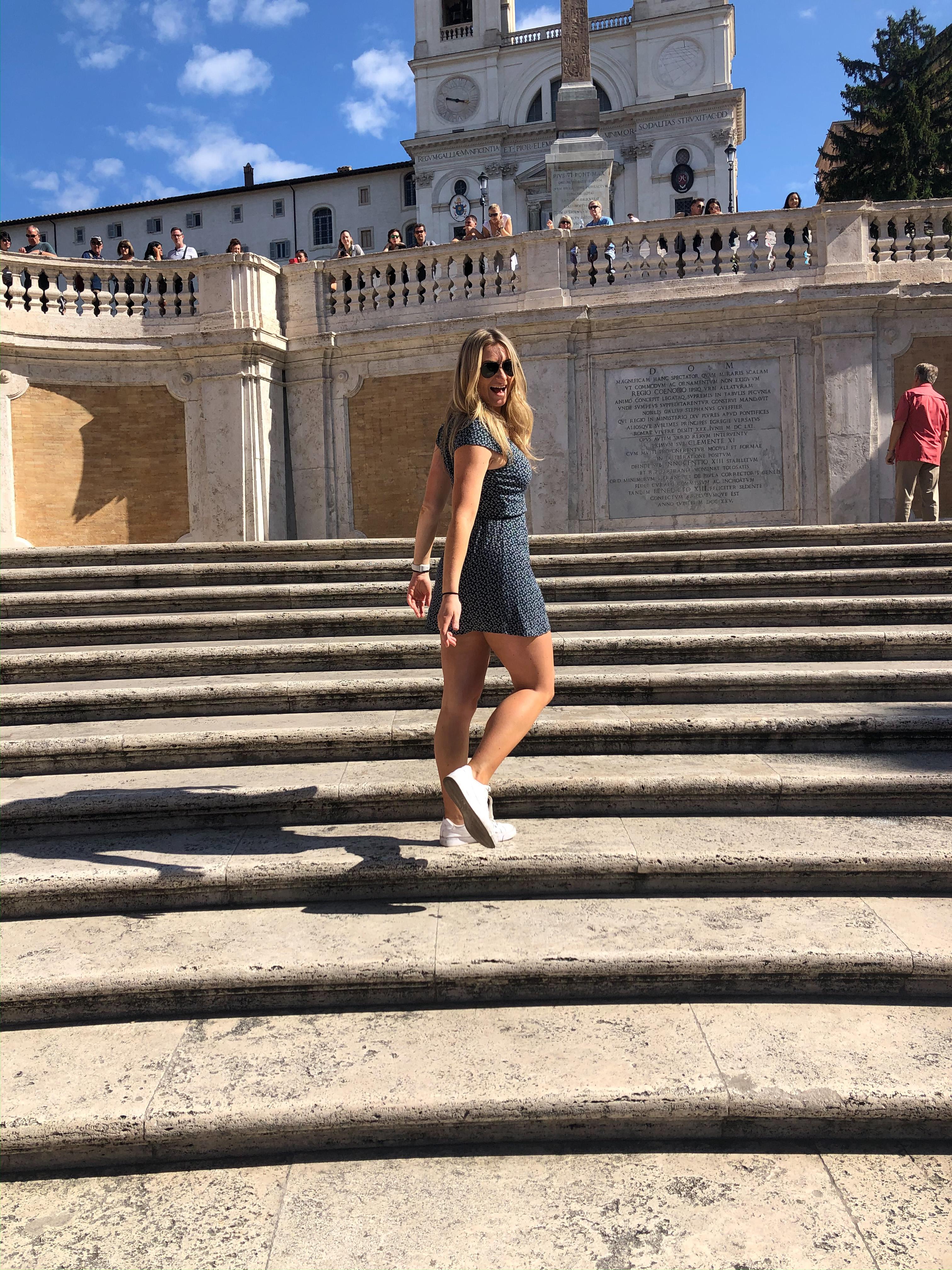 Student smiling while standing on steps at the foot of a terrace