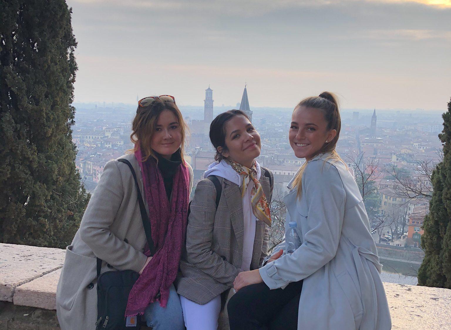 Three Fisher students sitting on ledge with view of Milan behind them.