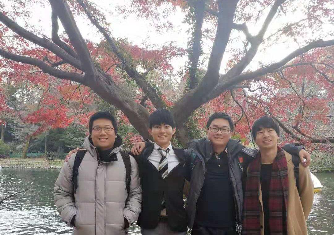 Group of students in Japan standing in front of a tree and flowing stream