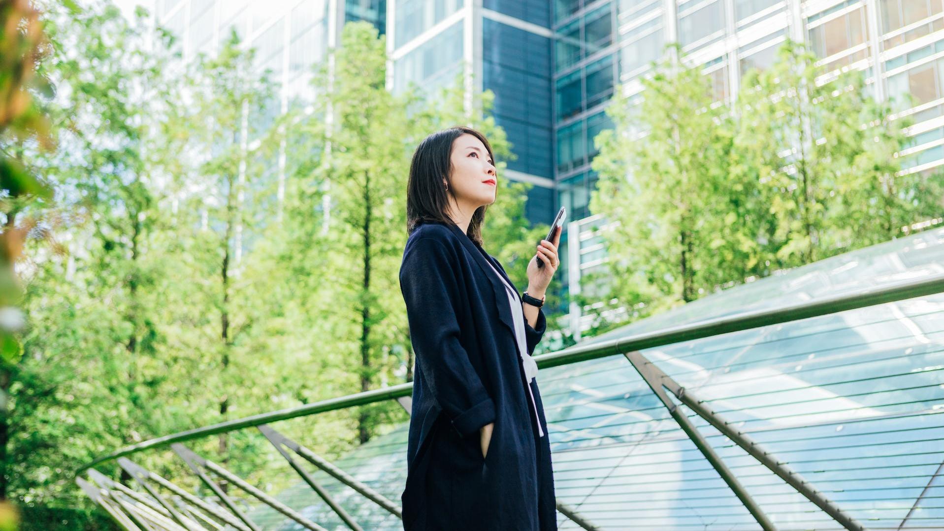 Business person holding a phone and looking up toward the sky