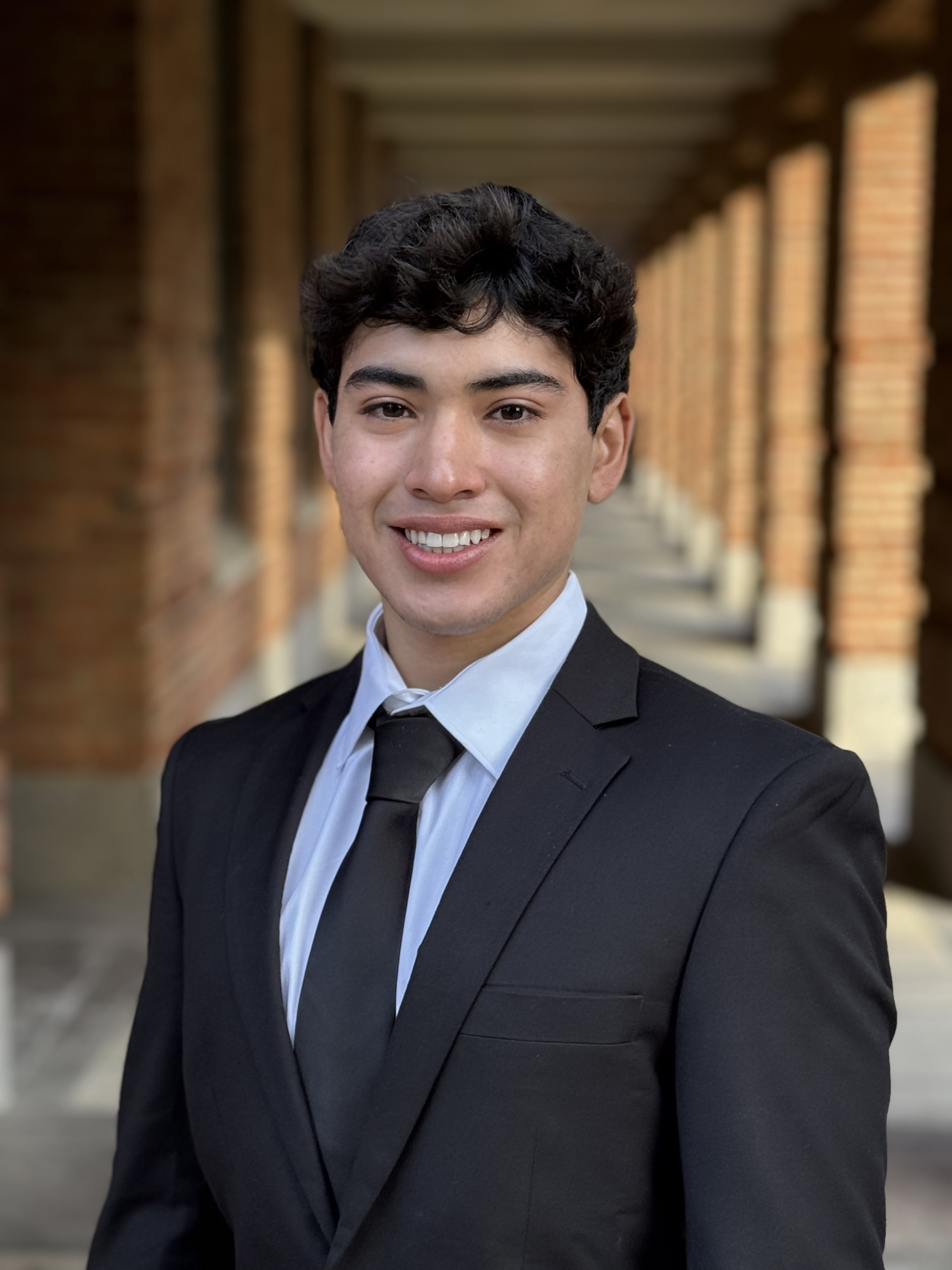 man smiling at the camera with a black tux and a black tie