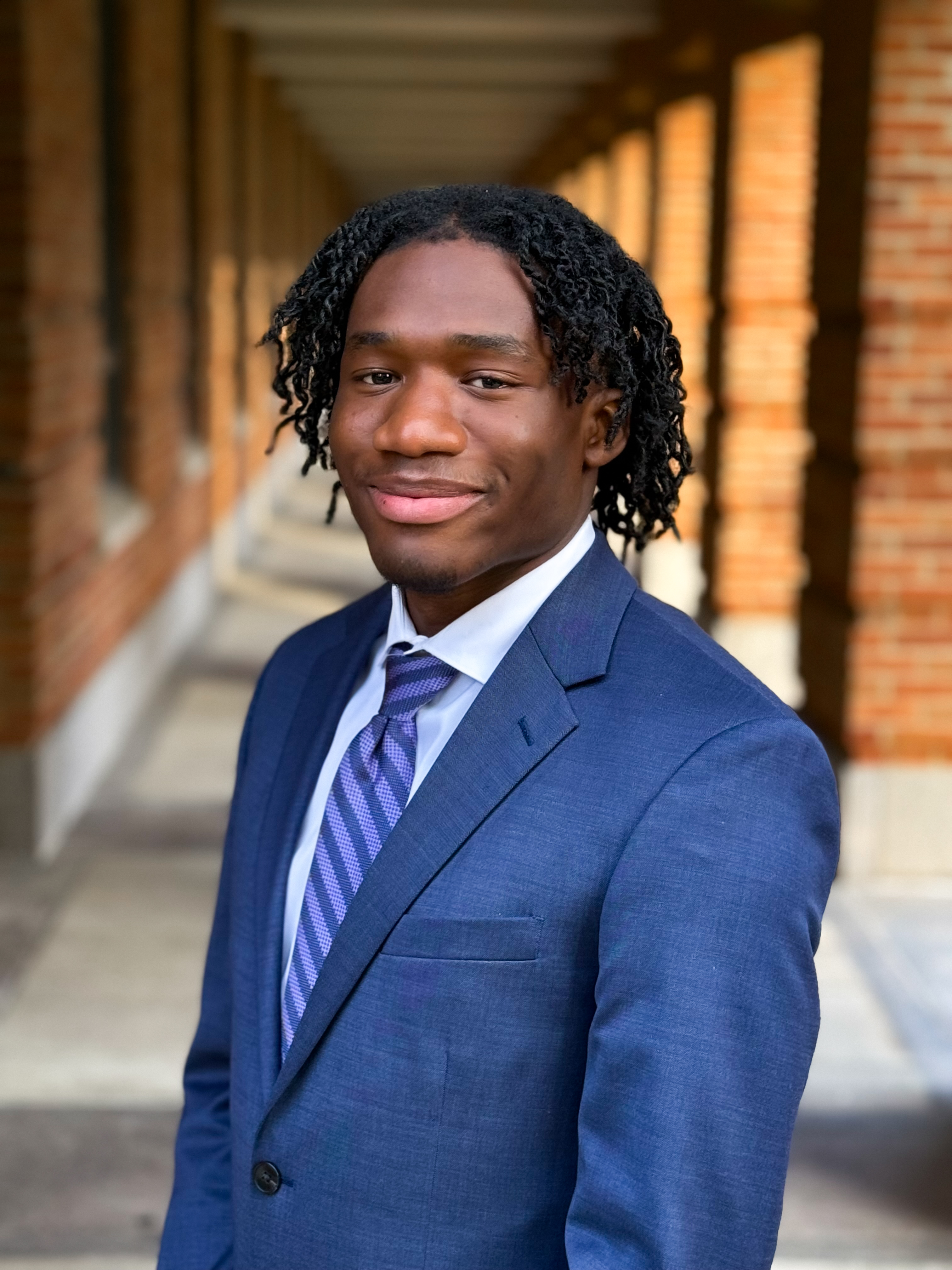 man with long hair smiling at the camera with blue tux and blue tie