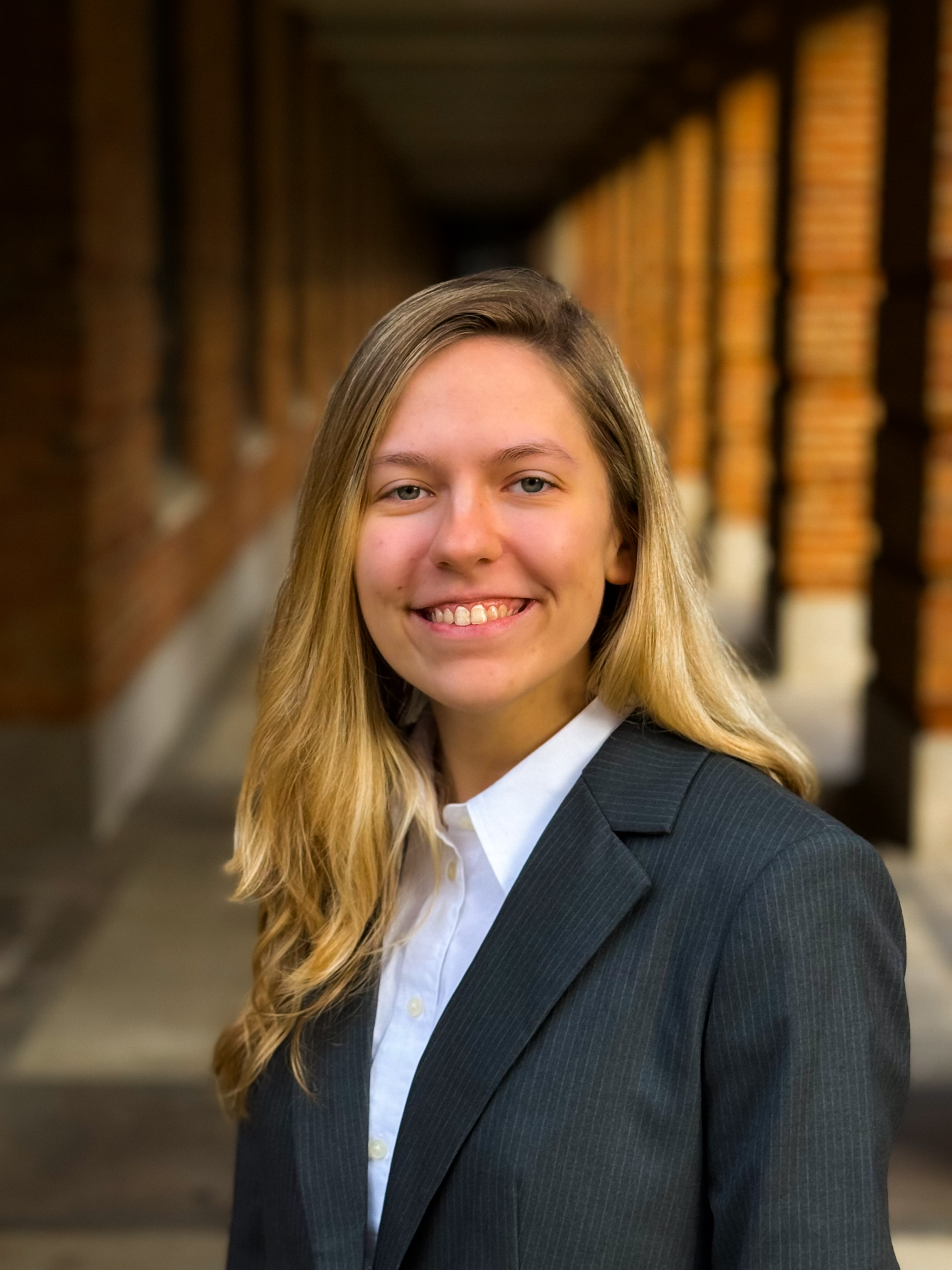 woman smiling at the camera with a black stripped suit jacket and white dress shirt