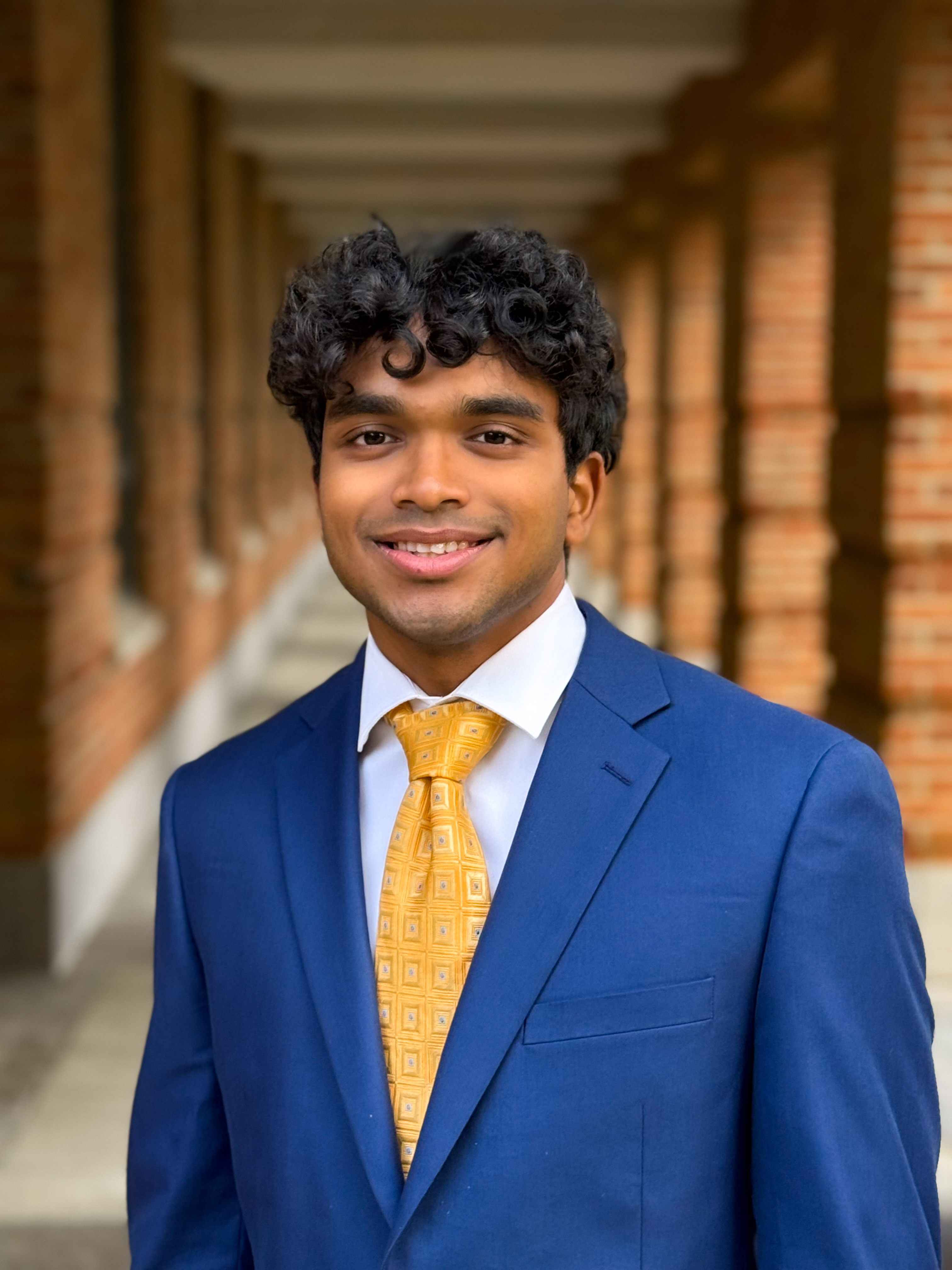 man smiling at the camera with a blue tux and yellow tie