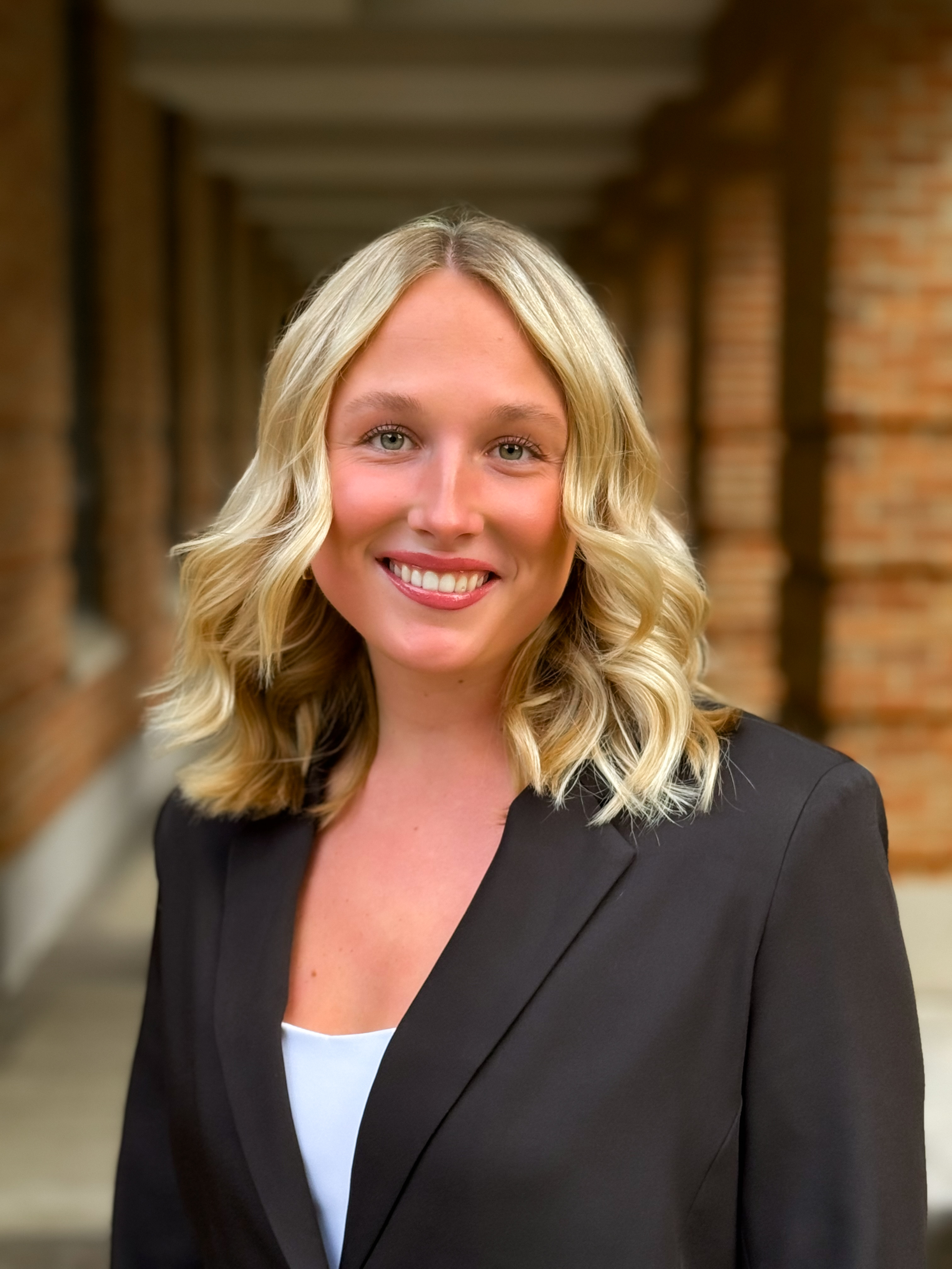 woman with blonde hair smiling at the camera with a black suit jacket