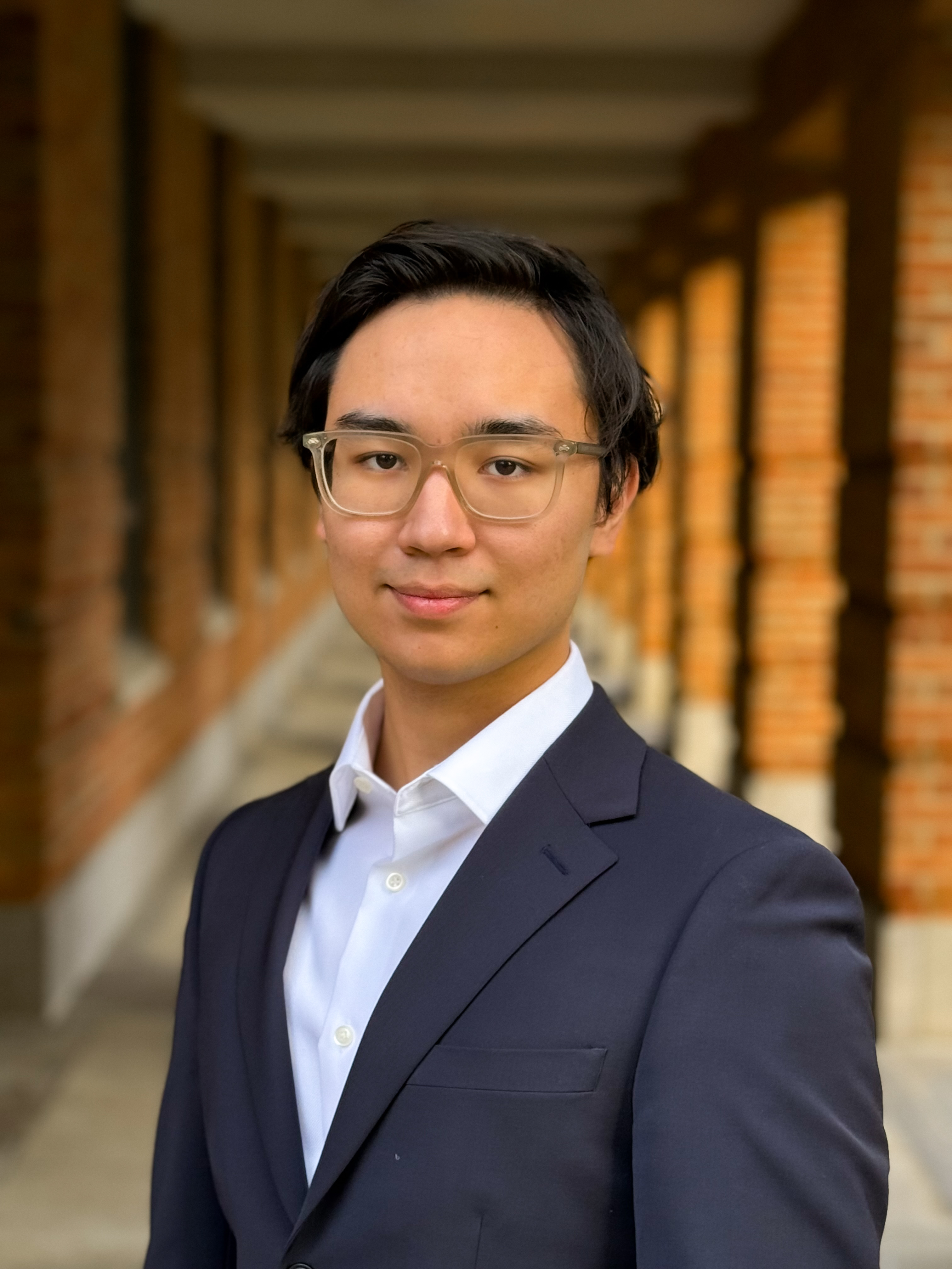man with glasses looking at the camera with a dark blue tux