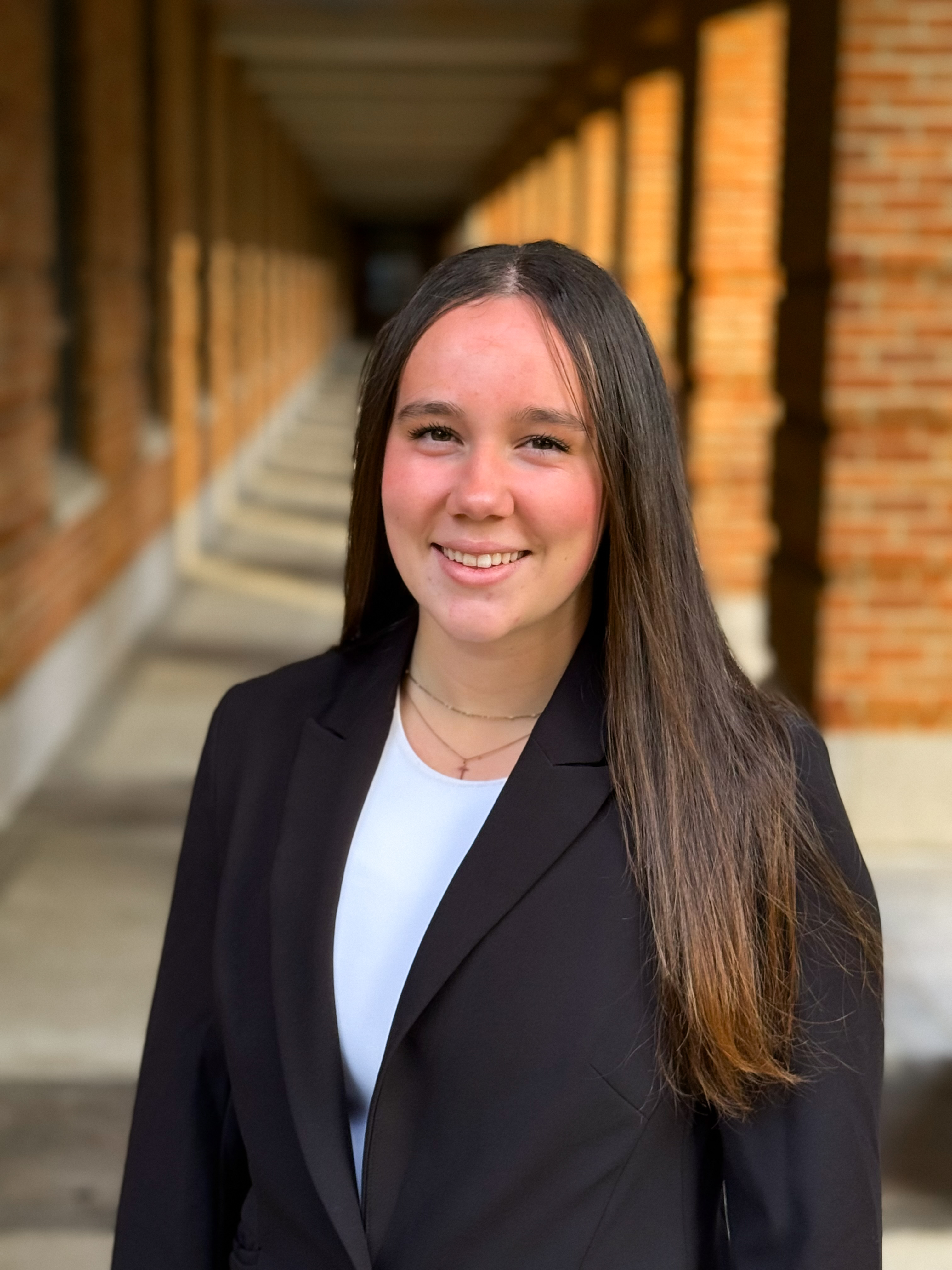 woman with dark hair smiling at the camera with black suit jacket and white dress shirt